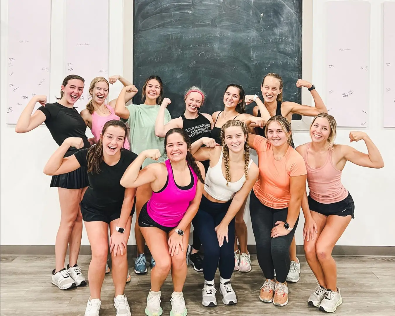 Group photo of sorority from Clemson University at Clemson Fitness Company, posing with instructor, flexing and smiling at camera.