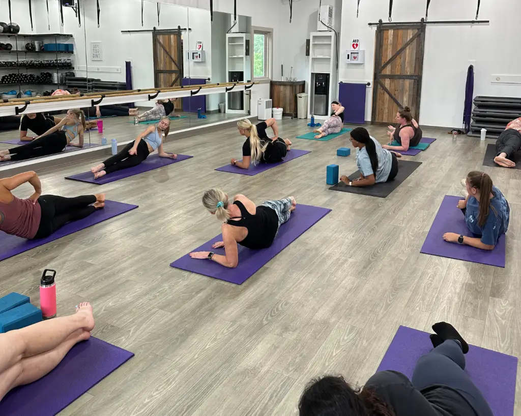 Group of students participating in a Pilates class at Clemson Fitness Company, using mats and props to improve strength and posture.