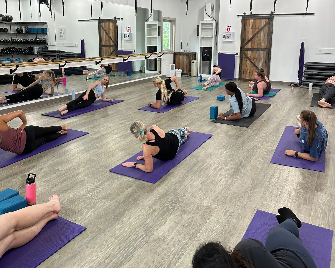 Group of students participating in a Pilates class at Clemson Fitness Company, using mats and props to improve strength and posture.